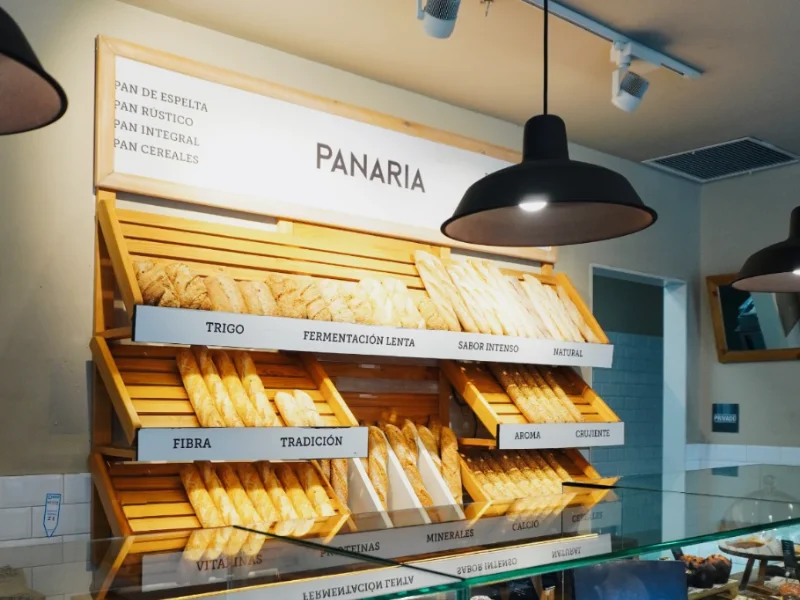 Interior de una panadería de la franquicia Panaria con exposición de panes artesanales y cartel corporativo.