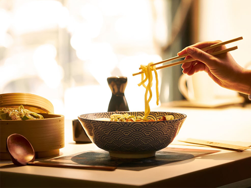 mujer comiendo el plato estrella dela franquicia Udon