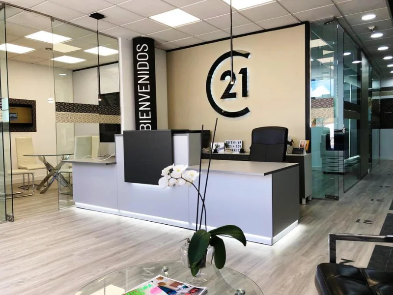 Oficina de la franquicia Century 21 España con recepción moderna y logotipo corporativo en la pared