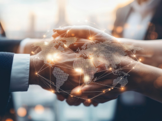 Manos estrechándose con un mapa del mundo digital superpuesto, simbolizando acuerdos internacionales y protección de marcas globales en franquicias.