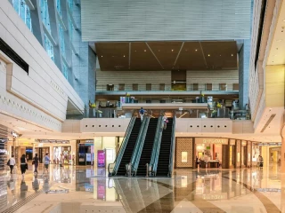 Interior de un centro comercial moderno con escaleras mecánicas y tiendas de franquicias de lujo en España