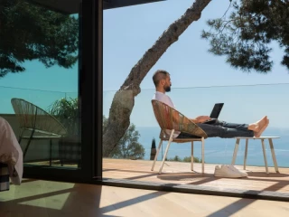 Emprendedor trabajando en verano desde la terraza frente al mar, inspiración para ideas de negocio y franquicias rentables en España