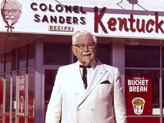 Coronel Sanders enfrente de un local de KFC