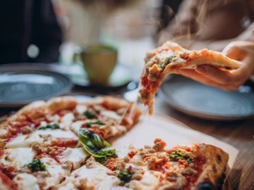 Pizza recién horneada servida en porciones, símbolo del crecimiento de las franquicias de pizzerías en España.
