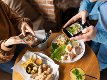 personas haciendo fotos a la comida en un restaurante