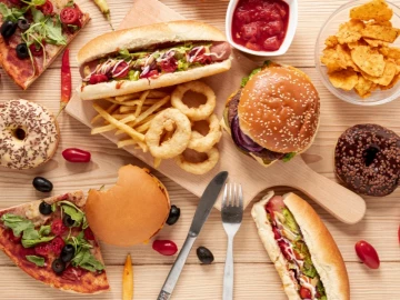 Comida rápida variada con hamburguesas, hot dogs, pizza y snacks, imagen representativa de franquicias de fast food en España.